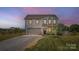 Charming two-story home at dusk featuring a freshly manicured lawn and a gravel driveway leading to the two-car garage at 2206 Mills Harris Rd, Wingate, NC 28174