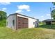 Spacious outbuilding with roll-up door offers versatile storage or workshop space, accented by green lawn at 237 Fea Ln, Iron Station, NC 28080
