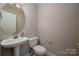 Cozy powder room featuring a pedestal sink, toilet, and neutral wall color at 2412 Laura Dr, Charlotte, NC 28212