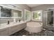 Elegant bathroom featuring double vanity, soaking tub, marble floors, and large, illuminated mirror at 3119 Castlemaine Dr, Charlotte, NC 28269