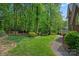 Large backyard offers lush lawn with mature trees and a walking path at 3124 Lakewood Edge Dr, Charlotte, NC 28269