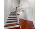 Bright entryway with wood staircase and floors leading to a white front door at 3507 Governors Island Dr, Denver, NC 28037