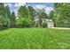 A lush green backyard with mature trees offers space for recreation and relaxation by the detached garage at 3950 Abingdon Rd, Charlotte, NC 28211