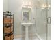 Stylish bathroom featuring a pedestal sink, modern fixtures, and a glass-enclosed shower, combining functionality with elegance at 3950 Abingdon Rd, Charlotte, NC 28211