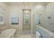 Luxurious bathroom featuring a soaking tub, marble tile, and a glass-enclosed shower at 3950 Abingdon Rd, Charlotte, NC 28211