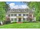 Stately white brick home featuring black shutters, dormer windows, and a manicured lawn at 3950 Abingdon Rd, Charlotte, NC 28211