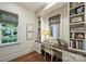 Cozy home office with built-in shelves, a wooden desk, and natural light from two windows at 3950 Abingdon Rd, Charlotte, NC 28211
