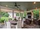 Relaxing outdoor seating area with a fireplace, multiple ceiling fans, and views of the lush backyard and garage at 3950 Abingdon Rd, Charlotte, NC 28211