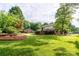 Landscaped backyard with mature trees, green grass, and a partial view of the home's exterior at 4145 Wrangler Sw Dr, Concord, NC 28027