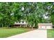 Charming home featuring a long driveway, a lush lawn, mature trees, and a three-car garage at 4145 Wrangler Sw Dr, Concord, NC 28027