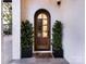 Arched wood front door with glass detailing, flanked by potted greenery and a 'hello' doormat at 443 Beaumont Ave, Charlotte, NC 28204