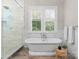 Bright bathroom featuring marble tile, soaking tub, and a separate glass-enclosed shower at 4635 Harper Ct, Charlotte, NC 28210