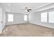 Spacious bedroom with soft carpet, tray ceiling, and ample natural light from three windows at 5146 Elementary View Dr, Charlotte, NC 28269