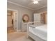 Neutral colored bedroom with dresser and round mirror on top with a doorway to the bathroom at 5951 Johnson Rd, Clover, SC 29710