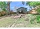 Large backyard with stepped retaining walls leading to a deck, and a backdrop of mature trees at 703 S Main St, Landis, NC 28088