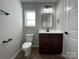 Bathroom featuring dark vanity with sleek fixtures, white countertop, toilet and a window at 113 Burke Cir, Mooresville, NC 28115