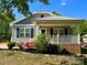 Charming single-story home featuring a metal roof, welcoming front porch, and beautiful landscaped flower beds at 113 Burke Cir, Mooresville, NC 28115