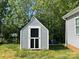 Backyard shed with gray siding and a black door surrounded by green foliage at 113 Burke Cir, Mooresville, NC 28115