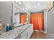 A bathroom with a double vanity, decorative mirror, and an orange shower curtain at 114 Doubletree Dr, Statesville, NC 28677