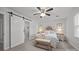 This main bedroom features a ceiling fan, neutral walls, and a sliding barn door that leads to the ensuite bathroom at 130 Cherokee Ln, Salisbury, NC 28147