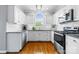 Well-lit kitchen with stainless steel appliances, granite countertops, white cabinets, and hardwood flooring at 1358 Colwick Ln, Rock Hill, SC 29732