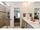 Bathroom and bedroom with double sinks, gray cabinets, glass-enclosed shower, leading to a cozy bedroom space at 15813 Capps Rd, Charlotte, NC 28278