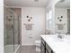 Modern bathroom with a glass-enclosed shower, vanity with countertop, and a window providing ample light at 1607 Tundra Ln, Denver, NC 28037