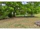 Secluded backyard with mature trees, a quaint bench, and lush greenery, creating a peaceful retreat for relaxation and nature enjoyment at 176 Jennymarie Rd, Mooresville, NC 28115