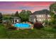 A luxurious backyard showcasing a large in-ground pool, well-manicured lawn, and beautiful landscaping with a house in the background at 2304 Thunder Gulch Ct, Waxhaw, NC 28173