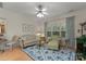Cozy living room with hardwood floors, floral sofa, armchair, ceiling fan, and natural light at 2304 Thunder Gulch Ct, Waxhaw, NC 28173