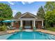 Outdoor pool with waterfall feature and lounging area, set against a brick pool house at 2304 Thunder Gulch Ct, Waxhaw, NC 28173