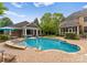 Inviting pool area with brick pool house, waterfall feature, lush landscaping, and seating area at 2304 Thunder Gulch Ct, Waxhaw, NC 28173