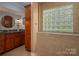 Elegant bathroom showcasing granite countertops, wood cabinetry, and glass block window for natural light at 2306 Beechwood Dr, Waxhaw, NC 28173