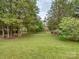 Large grassy backyard, featuring mature trees, fencing, and greenery at 2603 Willis Dr, Harrisburg, NC 28075