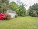 Large grassy backyard, featuring fencing, outbuilding, trees, and landscaping at 2603 Willis Dr, Harrisburg, NC 28075