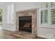 Stone fireplace with gas logs flanked by windows with shutters creating an inviting focal point at 2710 Red Bud Ln, Fort Mill, SC 29715