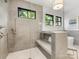 Tiled walk-in shower features a built-in bench, tiled walls, and natural light from a large window at 3505 Trent St, Charlotte, NC 28209