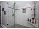 A modern bathroom shower features a glass door, tiled walls, and a built-in shelf for toiletries at 413 Nobles Way, Belmont, NC 28012
