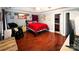 Spacious primary bedroom with a red bed, dark wood floors, and a massage chair at 4825 Samuel Richard St, Kannapolis, NC 28083
