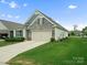 Well-maintained home featuring a stone facade, two-car garage, and lush green lawn with manicured landscaping at 5058 Antebellum Dr, Iron Station, NC 28080