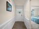 Bright hallway with paneled wainscotting, hardwood floors, leading to a bedroom with a blue bedspread at 5058 Antebellum Dr, Iron Station, NC 28080