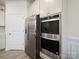 Stainless steel refrigerator and built-in double oven in a bright kitchen with gray wood-look flooring at 5058 Antebellum Dr, Iron Station, NC 28080