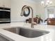 Close-up on a stainless steel sink and faucet on the kitchen island, with stainless oven in the background at 5058 Antebellum Dr, Iron Station, NC 28080