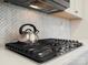 Close-up of the gas cooktop with stainless steel kettle and herringbone backsplash, in a bright kitchen at 5058 Antebellum Dr, Iron Station, NC 28080