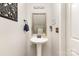 Well-lit powder room with pedestal sink, decorative mirror, and modern lighting at 5257 Glenlea Walk Ln, Charlotte, NC 28216