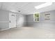 Neutral basement featuring new carpet, light gray walls, a window, and a white entry door at 5486 Suttlemyre Ln, Hickory, NC 28601