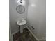 Powder room featuring an elegant pedestal sink and stylish round mirror with modern lighting at 6212 Snowcrest Ct, Charlotte, NC 28212
