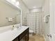 Well-lit bathroom features a large mirror, a shower with a checkered curtain, and neutral wall color at 6312 Kennard Dr, Charlotte, NC 28216