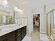 Modern bathroom with double vanity, a large mirror, and a walk-in closet with custom shelving at 6312 Kennard Dr, Charlotte, NC 28216