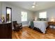Bright bedroom featuring hardwood floors, two windows, ceiling fan and rocking chair at 6616 Williams Rd, Charlotte, NC 28215